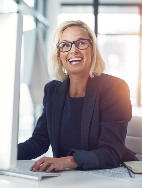 lachende blonde Frau, die an einem Computer sitzt